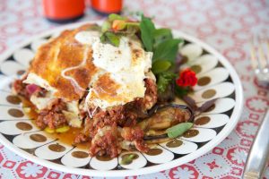 serving of moussaka on vintage plate with knife and fork