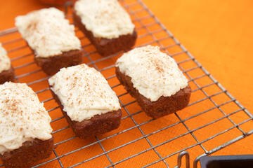 Mini gluten free and dairy free Carrot Cake loaves on wire rack and orange tablecloth