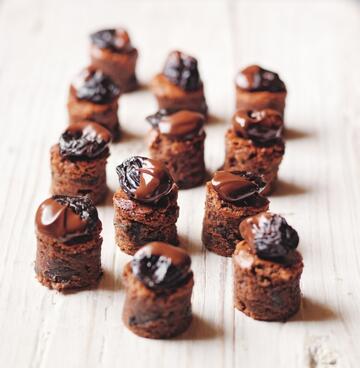 Mini chocolate and prune cakes on wooden chopping board