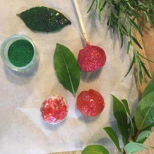 Festive decoration of Glitter and jam in bowls with rosemary and bay sprigs