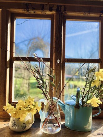 Easter floral decorations in vintage jugs on a window