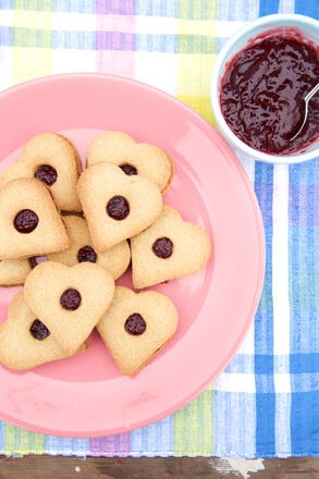 Gluten free heart shaped biscuits on pink plate with a bowl of jam