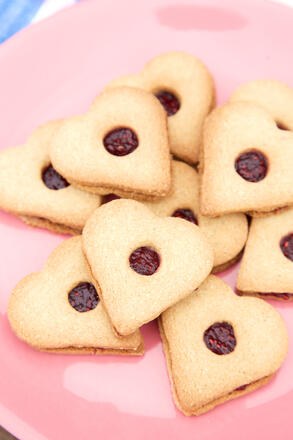 Heart shaped biscuits sandwiched with raspberry jam on pink plate