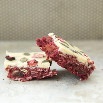 Pretty and colourful traybakes with coloured icing and scatterings of fruit, nuts and seeds on top